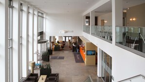 A spacious lobby with high ceilings, large windows, and a seating area with sofas and tables. - Atlantic Hotel Kiel (Kiel)