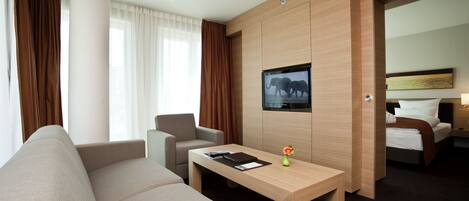 Een moderne hotelkamer met een bank, een klein tafeltje, een televisie en een bed.