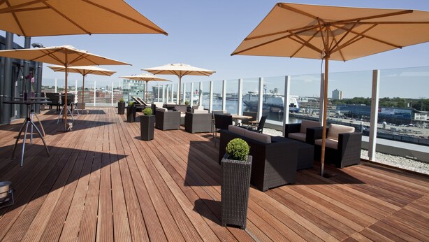 A rooftop terrace with wooden flooring, outdoor seating, and large umbrellas. - Atlantic Hotel Kiel (Kiel)