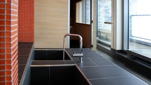 A modern bathroom with a large sink, a mirror, and a glass door leading to a balcony. - Atlantic Hotel Kiel (Kiel)