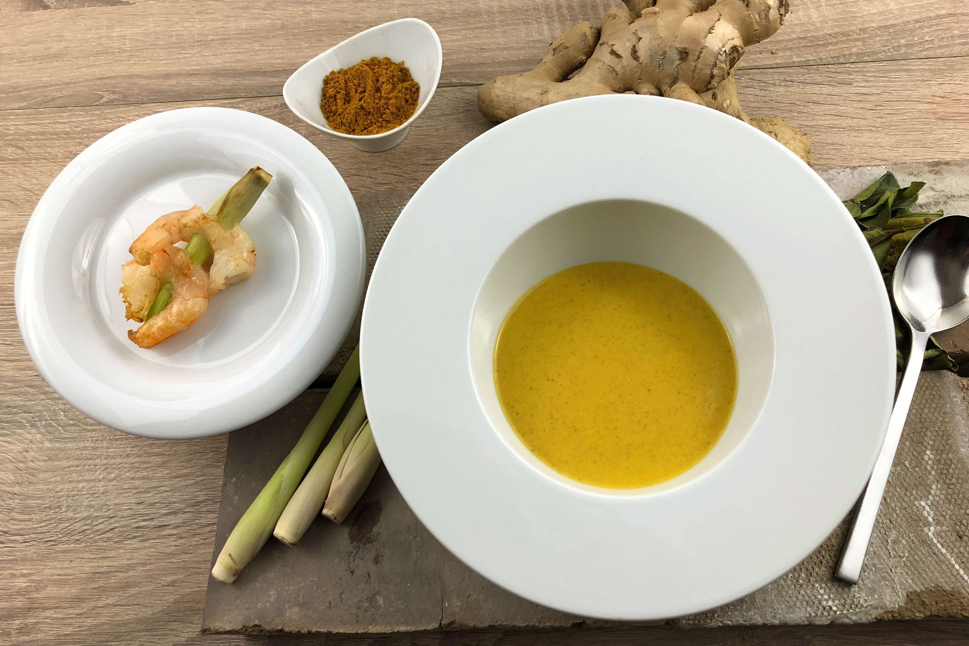 Un plato blanco con un tazón de sopa y un recipiente pequeño de especias.