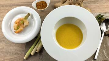 Un plato blanco con un tazón de sopa y un recipiente pequeño de especias.