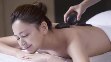 A person receiving a stone massage on a bed.