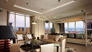 A modern living room with a sofa, coffee table, and a city view through large windows.