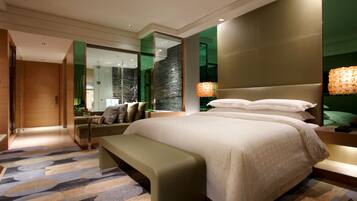 Una habitación de hotel moderna con una cama grande, un banco, un espejo y una pared verde.
