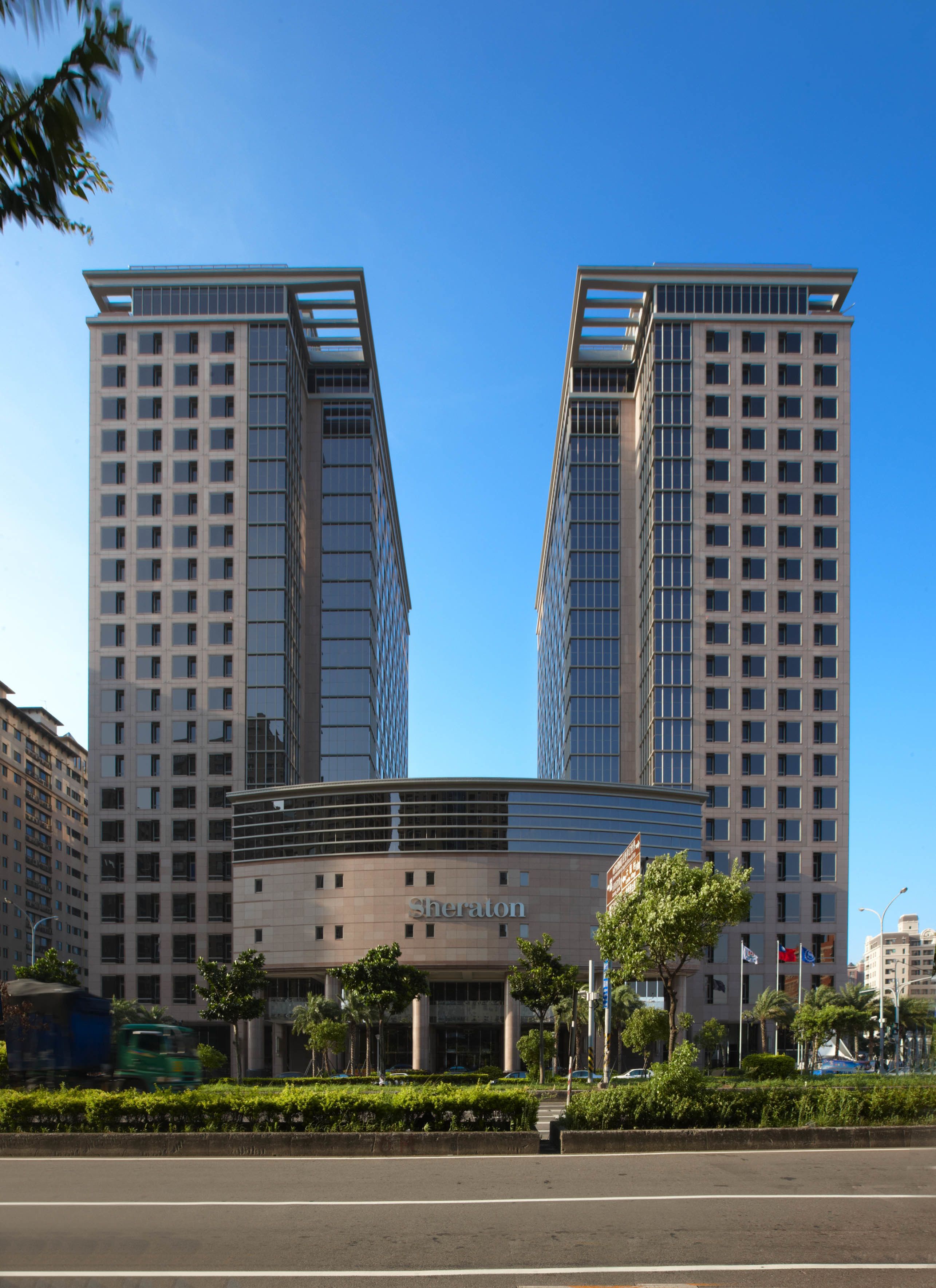 Een modern Sheraton hotel met een symmetrische gevel, grote ramen en een centrale ingang.