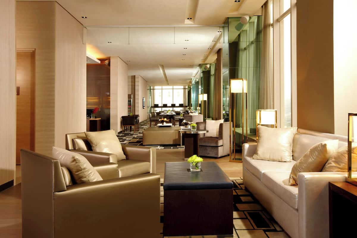 Een moderne hotellobby met een zithoek, een salontafel en een uitzicht op de keuken op de achtergrond.