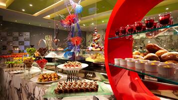 A buffet with various food items and desserts, including a display of cupcakes and a glass sculpture.