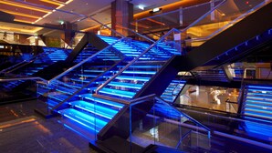 A modern interior with multiple glass staircases illuminated by blue lighting.