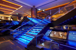 Un interior moderno con varias escaleras de cristal iluminadas con luces azules.