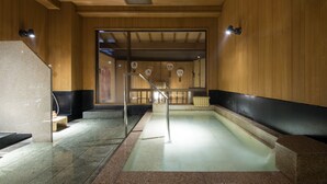 A traditional Japanese onsen with wooden walls, a stone pool, and a wooden staircase leading to a viewing area. - Shoheiso Ryokan (Izunokuni)