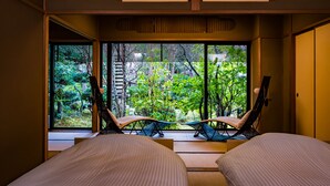 A room with two beds, a large window with a view of greenery, and two lounge chairs. - Shoheiso Ryokan (Izunokuni)