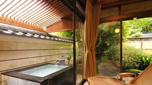 A traditional Japanese-style room with a tatami mat floor, a wooden ceiling, and a large window with a view of a garden. - Shoheiso Ryokan (Izunokuni)