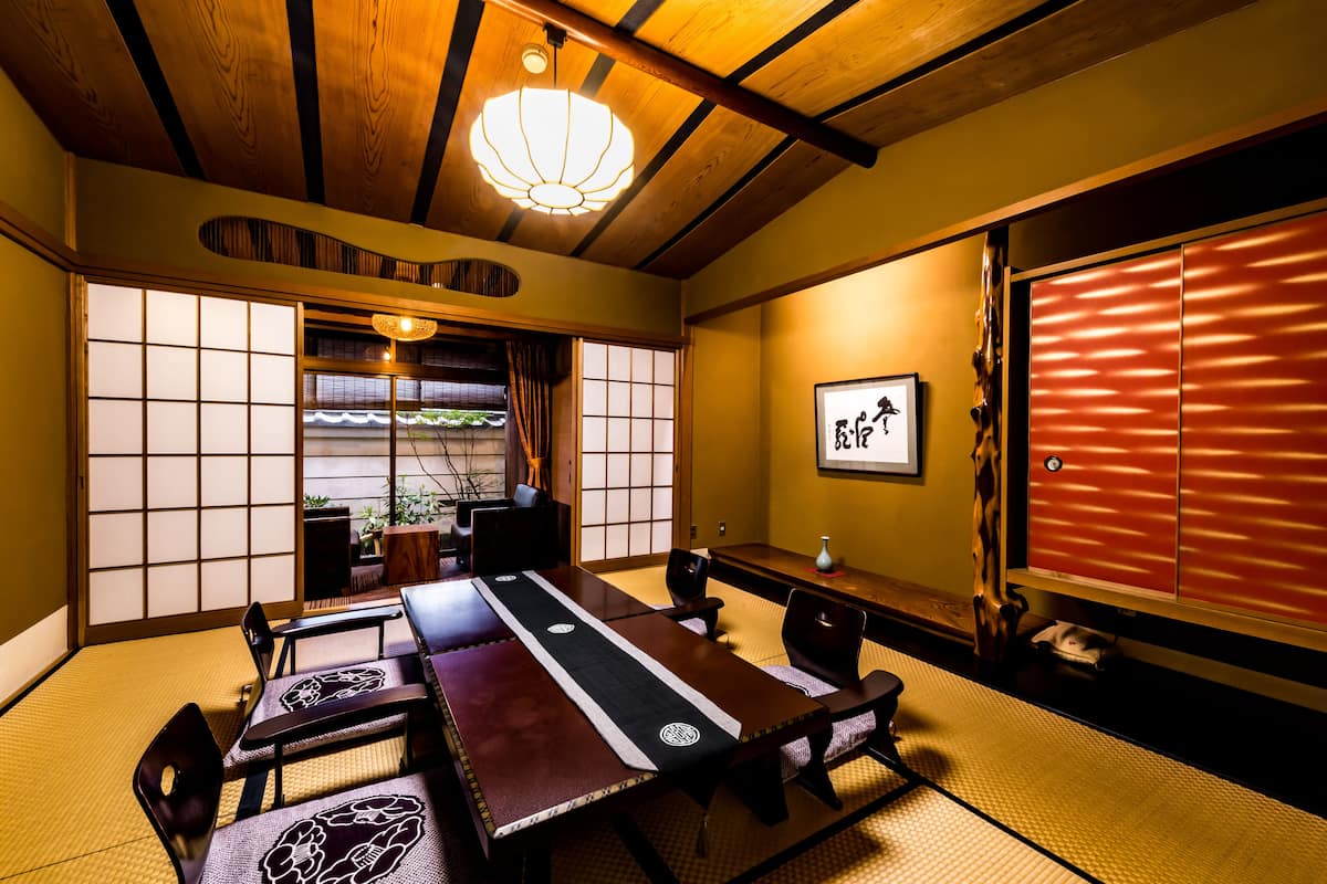 Una habitación japonesa tradicional con suelo de tatami, una mesa baja y puertas correderas.