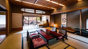 A traditional Japanese room with tatami flooring, a low table with cushions, and a view of the outside. - Shoheiso Ryokan (Izunokuni)