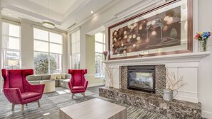 A spacious lobby with a fireplace, large windows, and modern seating. - Hilton Garden Inn Waldorf (Waldorf)