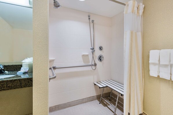 A bathroom with a shower, grab bar, and a bench.