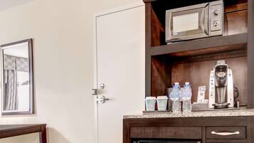 Una kitchenette con microondas, cafetera y botellas de agua.