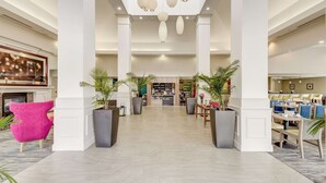 A spacious lobby with a central seating area, a bar, and a reception desk. - Hilton Garden Inn Waldorf (Waldorf)