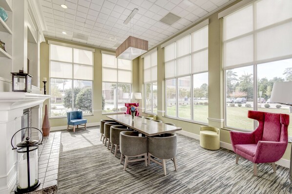 A spacious room with a large dining table, multiple chairs, and a vibrant red armchair.
