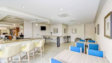 A modern dining area with a bar, multiple seating options, and a kitchen in the background.