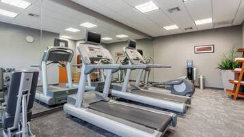 A fitness center with treadmills, a weight machine, and a water dispenser.