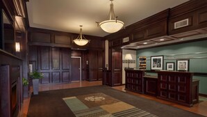 A lobby with a dark wood finish, a reception desk, and a patterned carpet. - Hampton Inn Detroit/Roseville (Clinton Township)