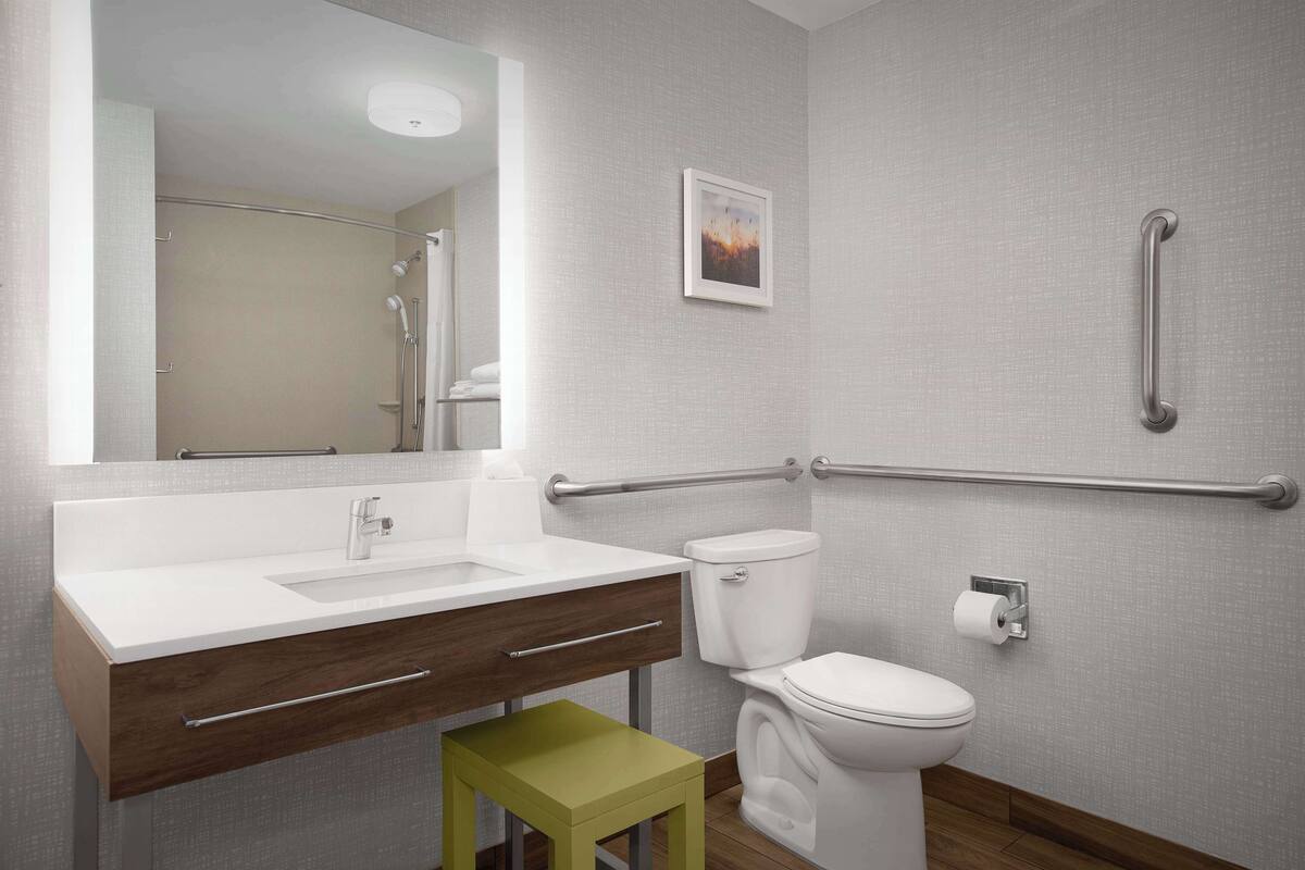Une salle de bain moderne avec un lavabo blanc, des toilettes et un tabouret vert.