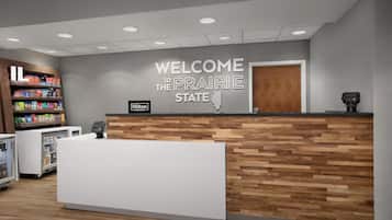 A reception desk with a 'Welcome to the Prairie State' sign, a minibar, and a vending machine.