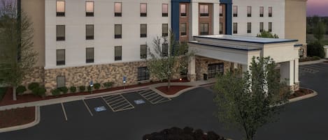 A Hampton Inn hotel with a modern design, a parking lot, and a clear sky.