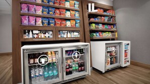 A snack and beverage display area with shelves stocked with various snacks and drinks, and two refrigerated display cases. - Hampton Inn Yorkville (Yorkville)