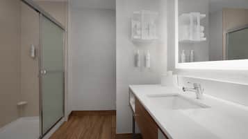 A modern bathroom with a shower, a vanity with a mirror, and toiletries.