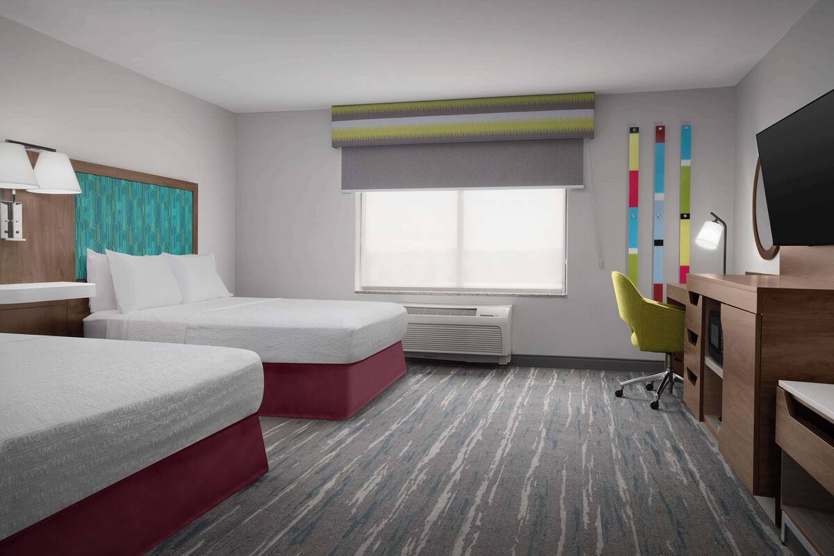 Une chambre d’hôtel avec deux lits, un bureau, une chaise, une télévision et une fenêtre donnant sur un beau paysage.