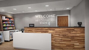 A reception area with a wooden reception desk, a "Welcome to the Prairie State" sign, a minibar, and a refrigerator. - Hampton Inn Yorkville (Yorkville)