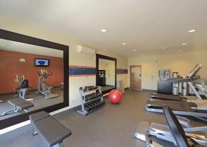 Une salle de sport équipée de tapis de course, de ballons d’exercice et d’appareils de musculation.