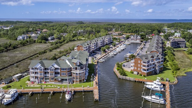 Un puerto deportivo con barcos amarrados, rodeado de edificios residenciales con balcones y vistas al agua.