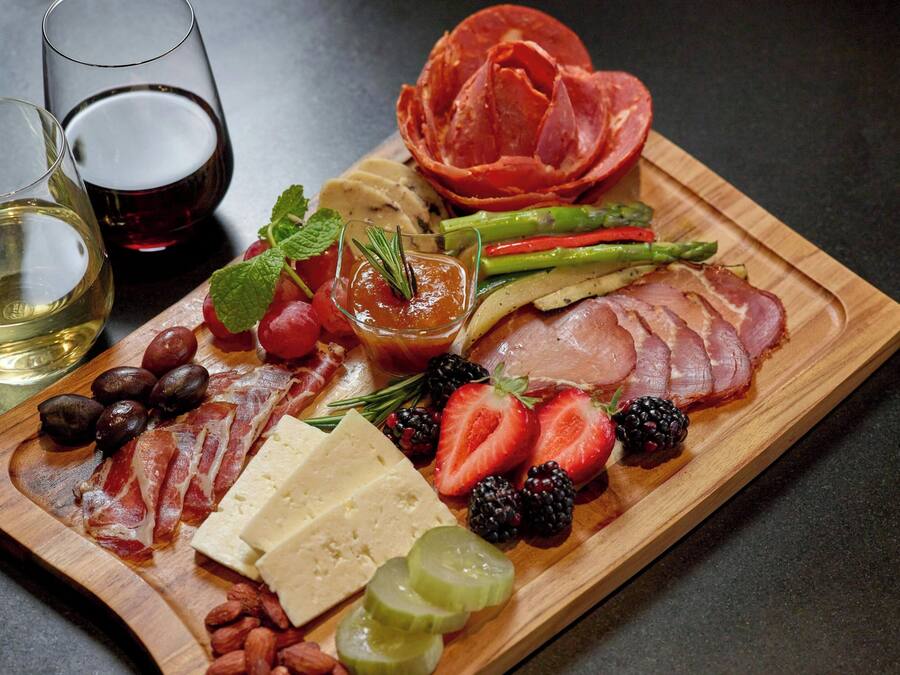 A charcuterie board with various meats, cheeses, fruits, and olives.