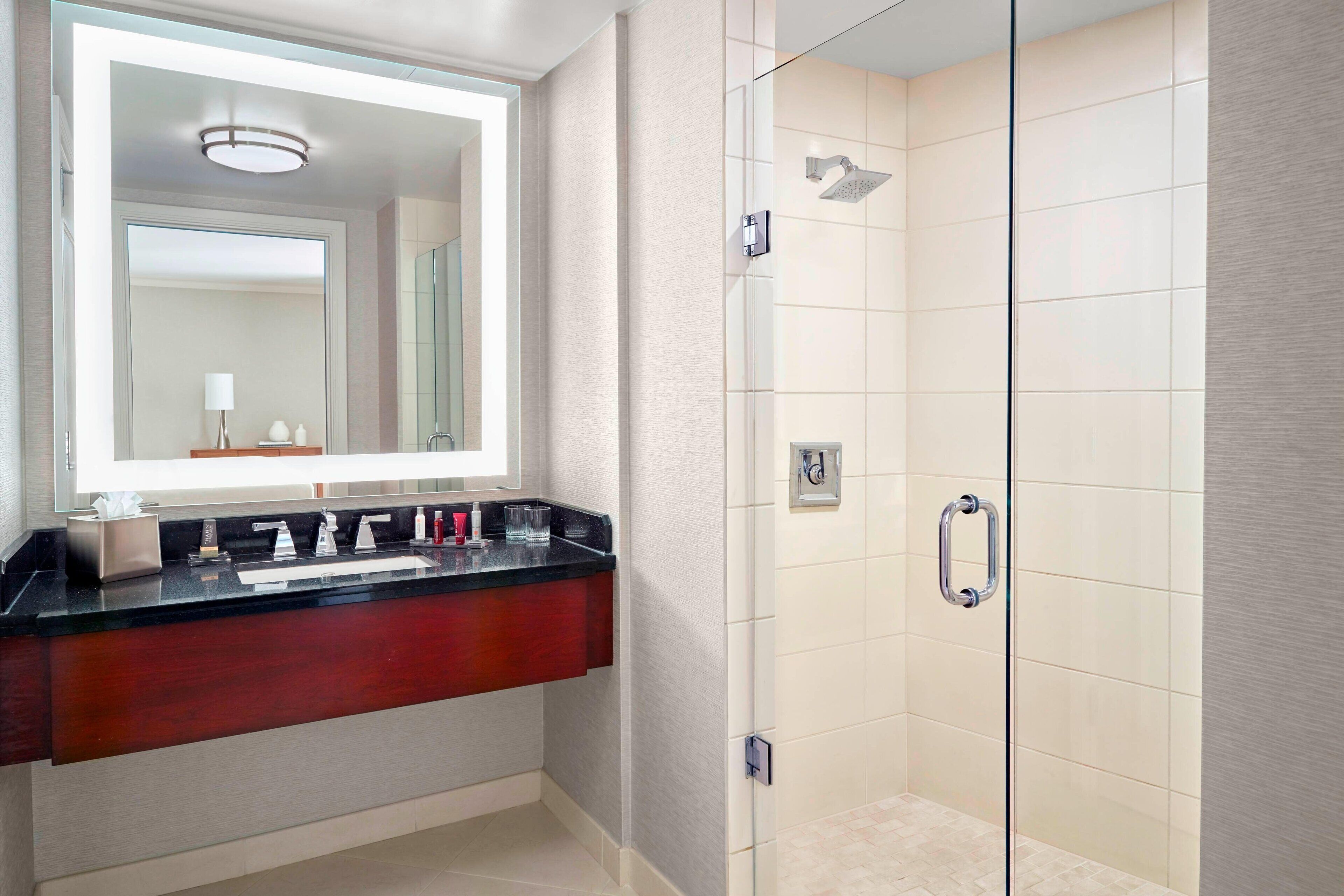 A modern bathroom with a glass-enclosed shower, a vanity with a mirror, and a light fixture.