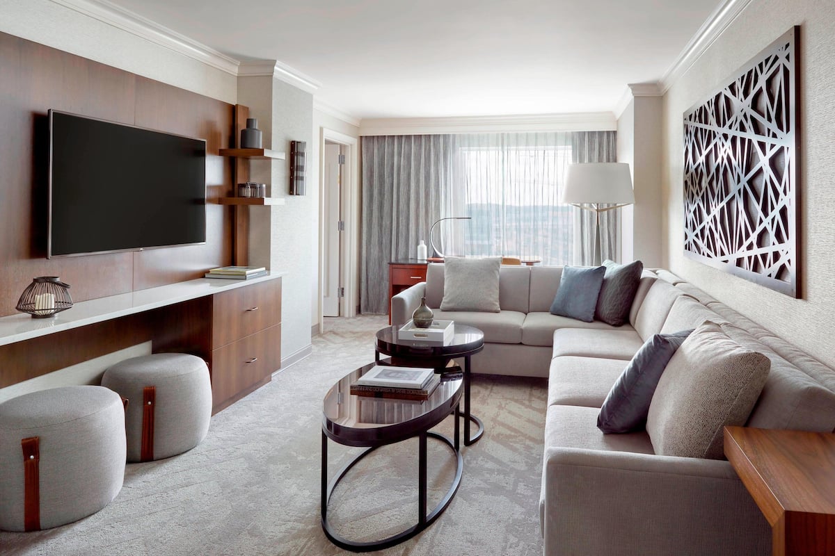 A modern living room with a flat-screen TV, a sofa, ottomans, and a coffee table.