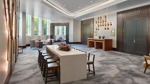 A modern hotel lobby with a central bar area, seating, and a reception desk. - Atlanta Airport Marriott Gateway (College Park)