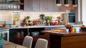 A modern kitchen with wooden cabinets, a built-in island, and various breakfast items. - Atlanta Airport Marriott Gateway (College Park)