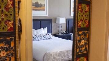 A hotel room with a bed, bedside table, lamp, and a mirror with decorative frames.