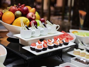 Een buffet met diverse gerechten, waaronder fruit, cupcakes en desserts.