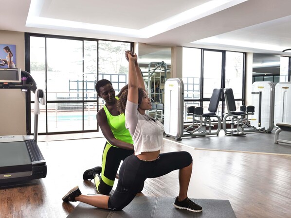 Une salle de sport équipée de matériel d’exercice, d’un tapis de course et dotée de grandes fenêtres.