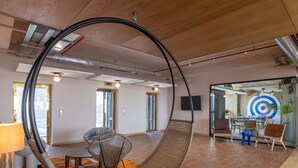 Un ufficio moderno con una poltrona sospesa, un'area pranzo e una sala riunioni con una lavagna.