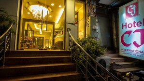 A hotel entrance with a grand staircase, a chandelier, and a sign for 'Hotel CJ International'. - Hotel CJ International (Amritsar)