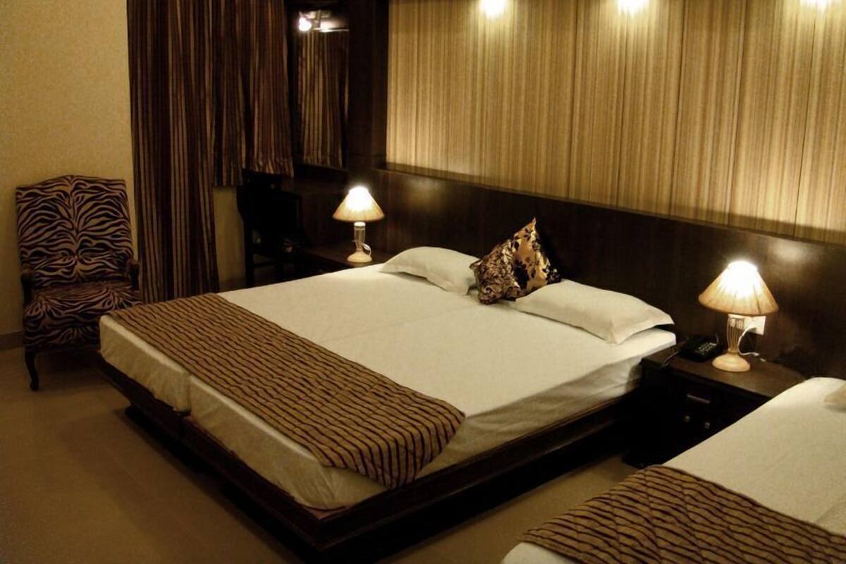 A hotel room with a large bed, two bedside tables with lamps, a zebra-patterned chair, and a headboard with vertical lines.
