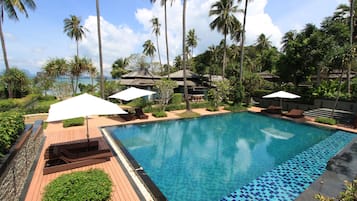 Una piscina al aire libre, sombrillas, sillones reclinables de piscina