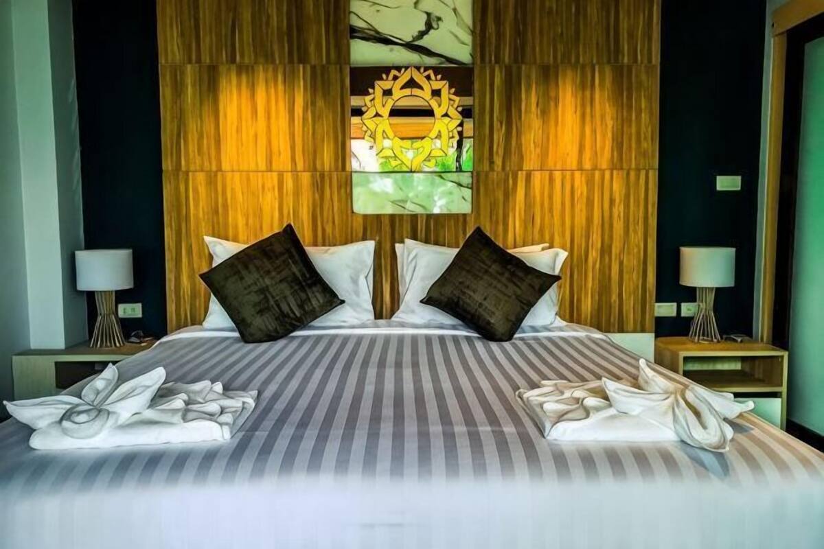 Una cama doble con una colcha a rayas, dos almohadas y un adorno en la pared superior.