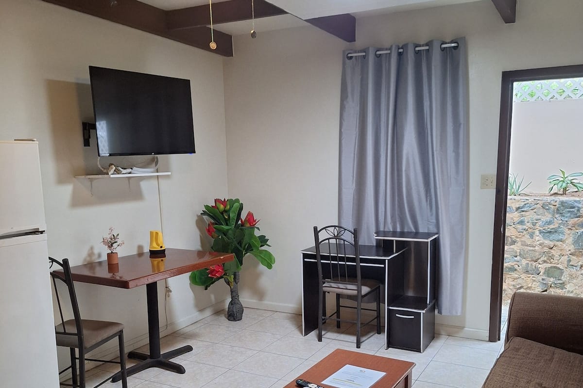 A living room with a TV, a dining table, chairs, a coffee table, and a sofa.